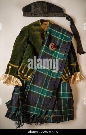 Une tenue de clan vintage de quatre ans, environ 1910, tartan inconnu avec broche écossaise, bonnet Glengarry et tartan Sash Banque D'Images