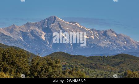 Un majestueux sommet de montagne enneigé s'élève au-dessus des forêts verdoyantes, montagnes Taygetos, péninsule de Mani, Péloponnèse, Grèce Banque D'Images