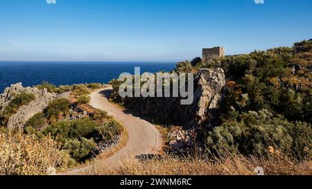 Route sinueuse le long des falaises côtières avec vue sur la mer et une ruine, péninsule de Mani, Péloponnèse, Grèce Banque D'Images
