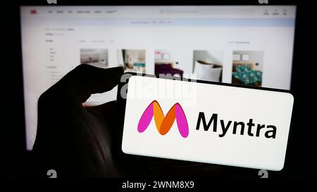 Personne tenant un smartphone avec le logo de la société indienne de commerce électronique Myntra Designs Pvt. Ltd en face du site Web. Concentrez-vous sur l'affichage du téléphone. Banque D'Images