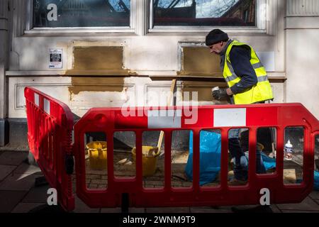 Londres, Royaume-Uni. 3 mars 2024. Un travailleur de la construction couvre les créneaux pour les distributeurs automatiques de billets et d'autres installations dans une ancienne succursale de la banque NatWest sur Chiswick High Road dans l'ouest de Londres. Alors que les banques migrent principalement vers des services en ligne et ferment des succursales physiques pour économiser de l'argent, les critiques disent que certains membres de la communauté sont laissés pour compte car ils dépendent de l'argent liquide, n'ont pas accès aux services bancaires en ligne et préfèrent un contact face à face avec le personnel de leur succursale locale. Credit : Stephen Chung / Alamy Live News Banque D'Images