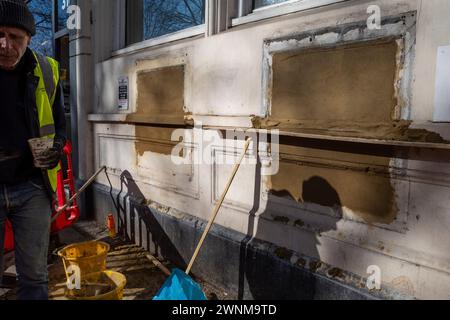 Londres, Royaume-Uni. 3 mars 2024. Un travailleur de la construction couvre les créneaux pour les distributeurs automatiques de billets et d'autres installations dans une ancienne succursale de la banque NatWest sur Chiswick High Road dans l'ouest de Londres. Alors que les banques migrent principalement vers des services en ligne et ferment des succursales physiques pour économiser de l'argent, les critiques disent que certains membres de la communauté sont laissés pour compte car ils dépendent de l'argent liquide, n'ont pas accès aux services bancaires en ligne et préfèrent un contact face à face avec le personnel de leur succursale locale. Credit : Stephen Chung / Alamy Live News Banque D'Images