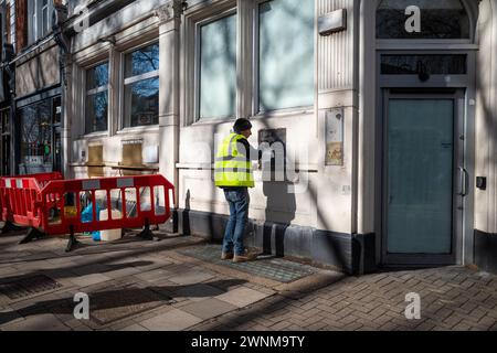 Londres, Royaume-Uni. 3 mars 2024. Un travailleur de la construction couvre les créneaux pour les distributeurs automatiques de billets et d'autres installations dans une ancienne succursale de la banque NatWest sur Chiswick High Road dans l'ouest de Londres. Alors que les banques migrent principalement vers des services en ligne et ferment des succursales physiques pour économiser de l'argent, les critiques disent que certains membres de la communauté sont laissés pour compte car ils dépendent de l'argent liquide, n'ont pas accès aux services bancaires en ligne et préfèrent un contact face à face avec le personnel de leur succursale locale. Credit : Stephen Chung / Alamy Live News Banque D'Images