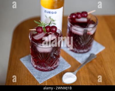 Berlin, Allemagne. 03 mars 2024. Deux verres de la boisson tendance «Sleepy Girl Mocktail» se tiennent sur une table à côté d'une cuillère à café remplie de poudre de magnésium. La boisson, composée de poudre de magnésium, de jus de cerise aigre, d’eau minérale, de sirop de sureau (facultatif) et de glaçons, aurait un effet inducteur de sommeil. Crédit : Monika Skolimowska/dpa/Alamy Live News Banque D'Images