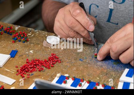 Fabricants de patio miniatures – Espagne. Avec les mains fermes, Rafael Aguilera place un petit pot de fleurs sur un aimant de réfrigérateur dans la ville historique de Cordoue dans et Banque D'Images