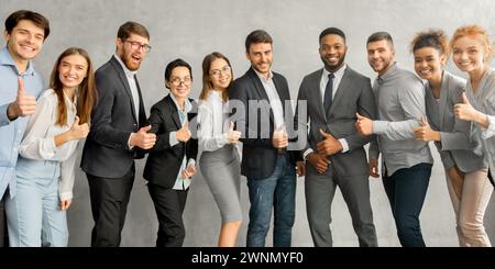Jeune équipe d'affaires joyeuse montrant les pouces vers le haut Banque D'Images