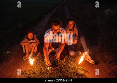 Dans la nuit enchanteresse, une famille enflamme des pétillants sur un sentier isolé, se prélasser dans la lumière chaleureuse et festive, créant ensemble des souvenirs inoubliables. Diversi Banque D'Images