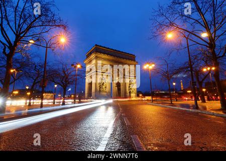 L'Arc de Triomphe dans la soirée pluvieuse. C'est l'un des monuments les plus célèbres de Paris. Il honore ceux qui se sont battus et sont morts pour la France. Banque D'Images