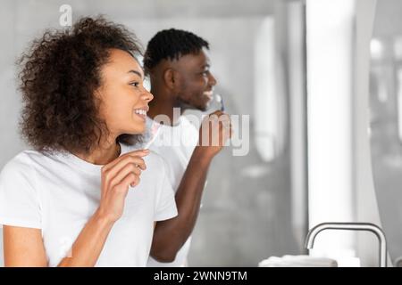 Portrait vue de côté de jeune couple noir se brossant les dents à l'intérieur Banque D'Images