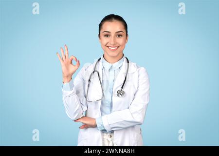 Jeune femme médecin donnant signe OK dans la blouse de laboratoire Banque D'Images