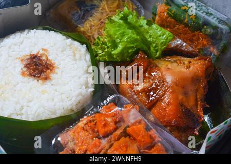 Concept alimentaire traditionnel d'Asie du Sud-est, riz enveloppé dans des feuilles de banane, poulet cuit dans de la sauce soja, salade de légumes et fruits, sur fond blanc Banque D'Images