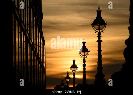 Comme le soleil se couche, les lampadaires ornés bordant la rive sud de la Tamise se silhouettent. Southbank, Londres, Royaume-Uni. 14 septembre 2023 Banque D'Images