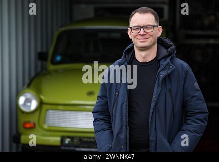 09 février 2024, Saxe, Zwickau : Frank Hofmann se tient dans les locaux de sa société Trabandout à côté d'un Trabant P 601 fidèlement reconstruit. Le détaillant en ligne propose toutes les pièces du Trabant comme pièces de rechange. Le Trabant 601 a été présenté au public international il y a 60 ans à la foire du printemps de Leipzig. Il a remplacé les modèles précédents Trabant 500 (P 50) et 600 (P 60). Jusqu'à la réunification, plus de 2,8 millions des 601 ont été construites à Zwickau, ce qui en fait le modèle Trabant le plus vendu. Les chiffres d'enregistrement en Allemagne augmentent à nouveau depuis plusieurs années : selon la Fed allemande Banque D'Images