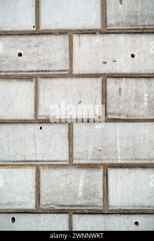 Un mur industriel blanc avec briques et taches et coulis foncé Banque D'Images