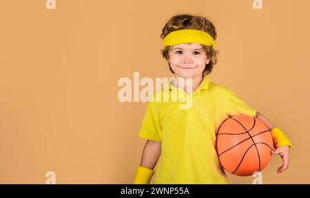 Garçon souriant en vêtements de sport avec ballon de jeu. Petit joueur de basket-ball en uniforme sportif. Mode de vie sain et loisirs. Sport pour enfants. Enfant sportif Banque D'Images