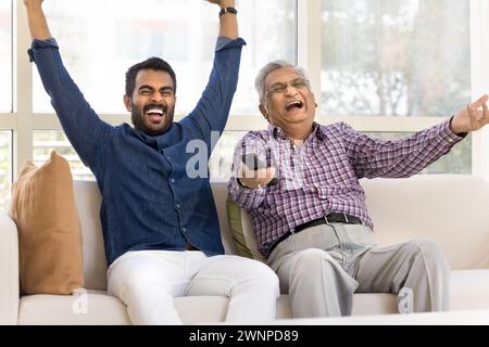 Joyeux père indien âgé excité et fils adultes regardant un match Banque D'Images