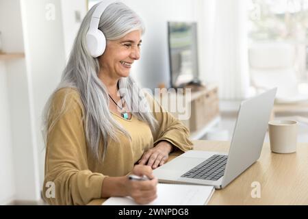 Heureuse femme étudiante âgée intelligente réussie utilisant un ordinateur portable Banque D'Images