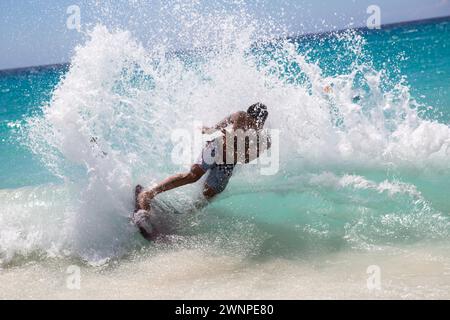 Les habitants chevauchent les vagues sur une plage de sable blanc à Hawaï. Banque D'Images