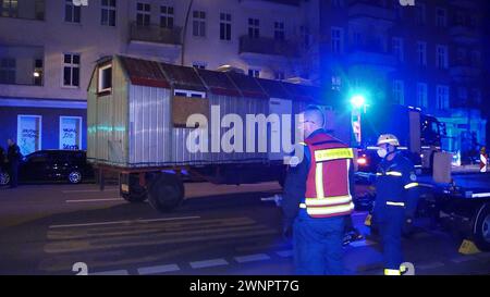 Berlin, Allemagne. 04 mars 2024. La remorque de construction, qui a été confisquée dans le cadre de la chasse à l'homme des terroristes de l'ex-RAF recherchés Staub et Garweg, est remorquée par un camion THW. Tôt lundi matin, la police a fait retirer la remorque de construction d'un autre site de gauche à Berlin. Crédit : Dominik Totaro/dpa/Alamy Live News Banque D'Images