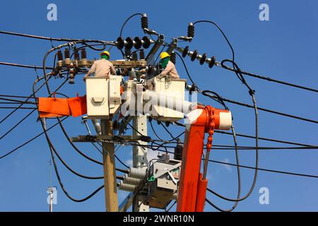l'équipe d'ingénierie électrique travaillant sur le berceau de la plate-forme aérienne ou de la grue a connecté des lignes de transmission haute tension au transformateur haute tension monté Banque D'Images