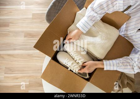 Femme emballant des vêtements et des chaussures dans la boîte en carton saisonnier rangement confortable organiser la vue de dessus Banque D'Images