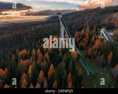 Strbske Pleso, Slovaquie - vue aérienne de la rampe de saut courbe pour le saut à ski dans les Hight Tatras près de Strbske Pleso avec des nuages dorés au coucher du soleil et colo Banque D'Images