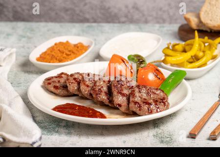 Boulettes de viande grillées. Avec tomates, poivrons, hors-d'œuvre et sauce spéciale. Boulettes de viande turques sur une assiette Banque D'Images