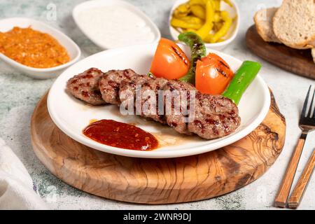 Boulettes de viande grillées. Avec tomates, poivrons, hors-d'œuvre et sauce spéciale. Boulettes de viande turques sur une assiette Banque D'Images