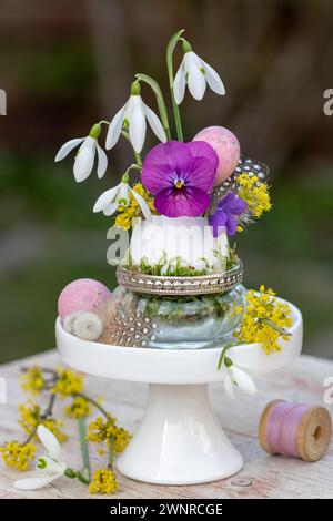 Arrangement de fleurs de pâques avec fleur d'alto, gouttes de neige et fleur de cerisier Cornelian dans l'œuf Banque D'Images