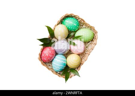 Panier d'œufs de Pâques colorés isolés sur fond blanc. Panier de Pâques rempli d'œufs de couleur vue du dessus concept de vacances . Banque D'Images