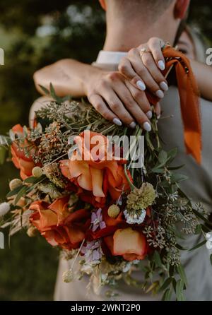 Mariée tenant des fleurs colorées sur les maris en arrière Banque D'Images