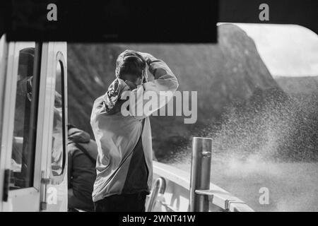 Tourist Man prend une photo lors d'une excursion en bateau venteux à Milford Sound Banque D'Images