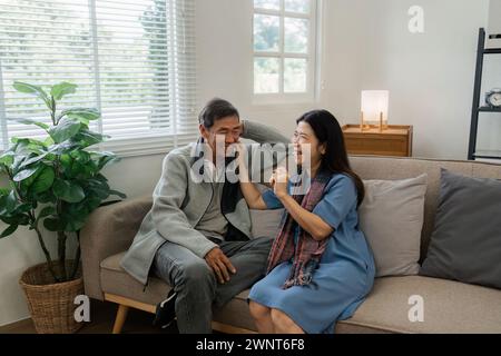 Les couples plus âgés s'assoient et discutent et se dirigent l'un sur l'autre détendus et heureux sur le canapé à la maison en semaine dans le confort Banque D'Images