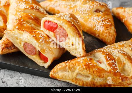 Porcs en couvertures pâte feuilletée rotation avec saucisse, fromage et poivre gros plan sur une planche de marbre sur la table. Horizontal Banque D'Images