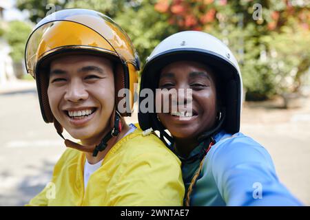 Passager heureux dans le casque prenant selfie avec chauffeur de taxi moto Banque D'Images