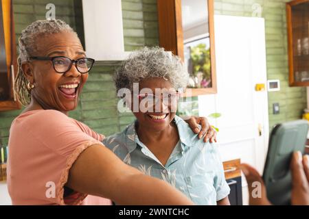 Femme afro-américaine senior et femme biraciale senior partagent un moment joyeux en prenant un selfie Banque D'Images