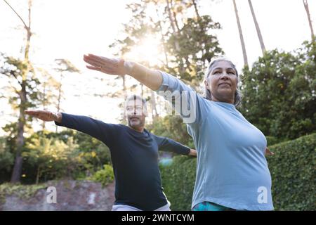 Femme biraciale senior et homme pratiquent le yoga à l'extérieur à la maison Banque D'Images