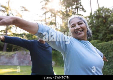 Femme biraciale senior avec les cheveux gris sourit tout en s'étirant à l'extérieur à la maison Banque D'Images