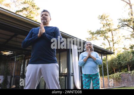 Couple biracial senior pratique le yoga en plein air, à la maison Banque D'Images