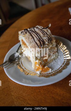 Pâtisserie suédoise Budapest avec meringue aux noisettes et mandarines sur une assiette avec une fourchette Banque D'Images