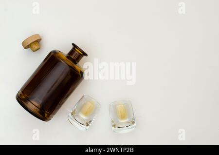 Deux verres à whisky vides avec une bouteille de whisky sur un fond gris clair. Vue de dessus. Banque D'Images