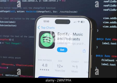 New York, USA - 23 février 2024 : Spotify sur l'écran de l'iphone en arrière-plan de programmation de code flou Banque D'Images