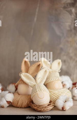 Oeufs de Pâques dans des chapeaux tricotés au crochet avec des oreilles de lapin dans le nid. Concept de célébration de Pâques Banque D'Images