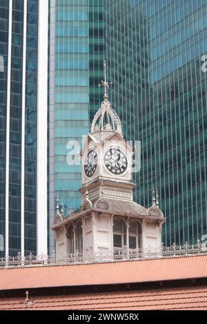 Tour de l'horloge de style colonial à Lau Pa Sat le centre des vendeurs de nourriture à Singapour contraste avec les blocs de verre modernes derrière son architecture Banque D'Images