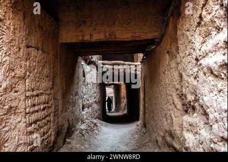 Femme marchant dans une ruelle couverte dans le village historique de Mhamid, Maroc Banque D'Images