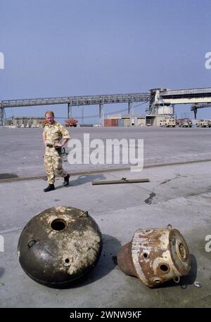 Première Guerre du Golfe : 20 mars 1991 sur le quai dans le port de Shuaiba, Koweït, un commandant de la Royal Navy passe devant quelques mines irakiennes en panne. Banque D'Images