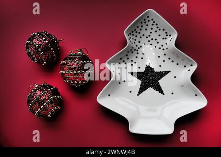 Arbre de Noël avec des ornements en or et une étoile au milieu. Fond rouge. Décorations de Noël. Ballons rouges avec des bandes dorées. Contraste accru Banque D'Images