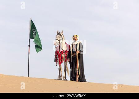 Hommes saoudiens avec sa fourrure debout à côté d'un drapeau saoudien Banque D'Images