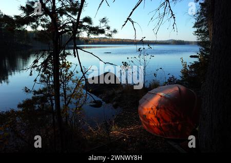 Vieux bateau rouge à l'envers sur la rive du lac en Suède, vue depuis Bruksleden sentier de randonnée près du lac Billsjon Banque D'Images