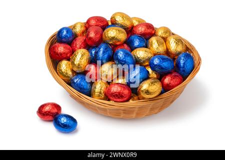 Panier avec des oeufs de pâques au chocolat en papier d'aluminium coloré Fermer isolé sur fond blanc Banque D'Images